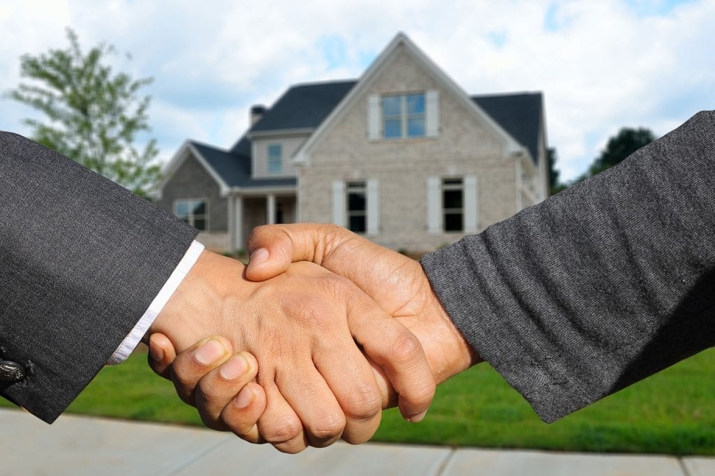 two hands shake to make an offer on a home